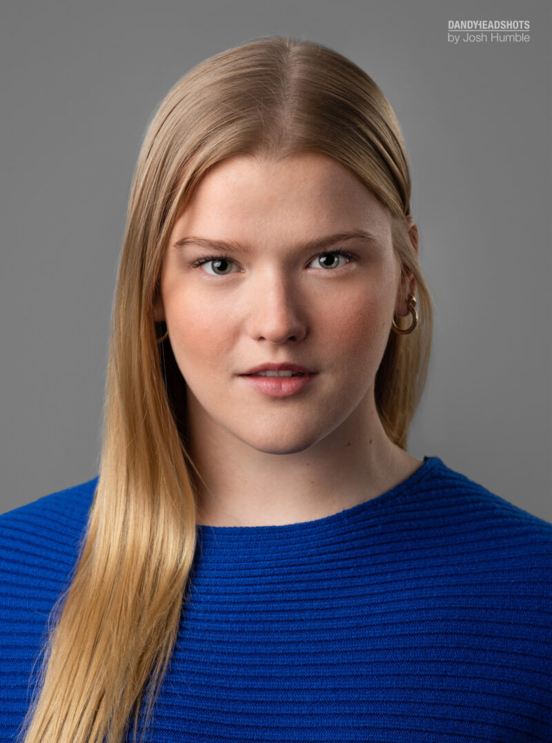 Actress headshot, vertical, grey background.